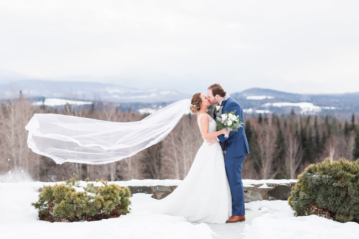 Bride and Groom kissing with veil floating in the air