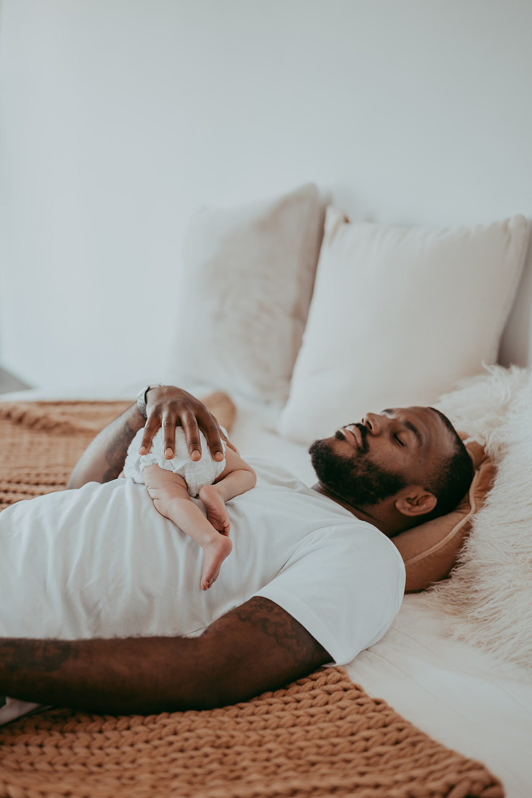 newborn baby's little legs as she sleeps on her stomach on her dad's chest