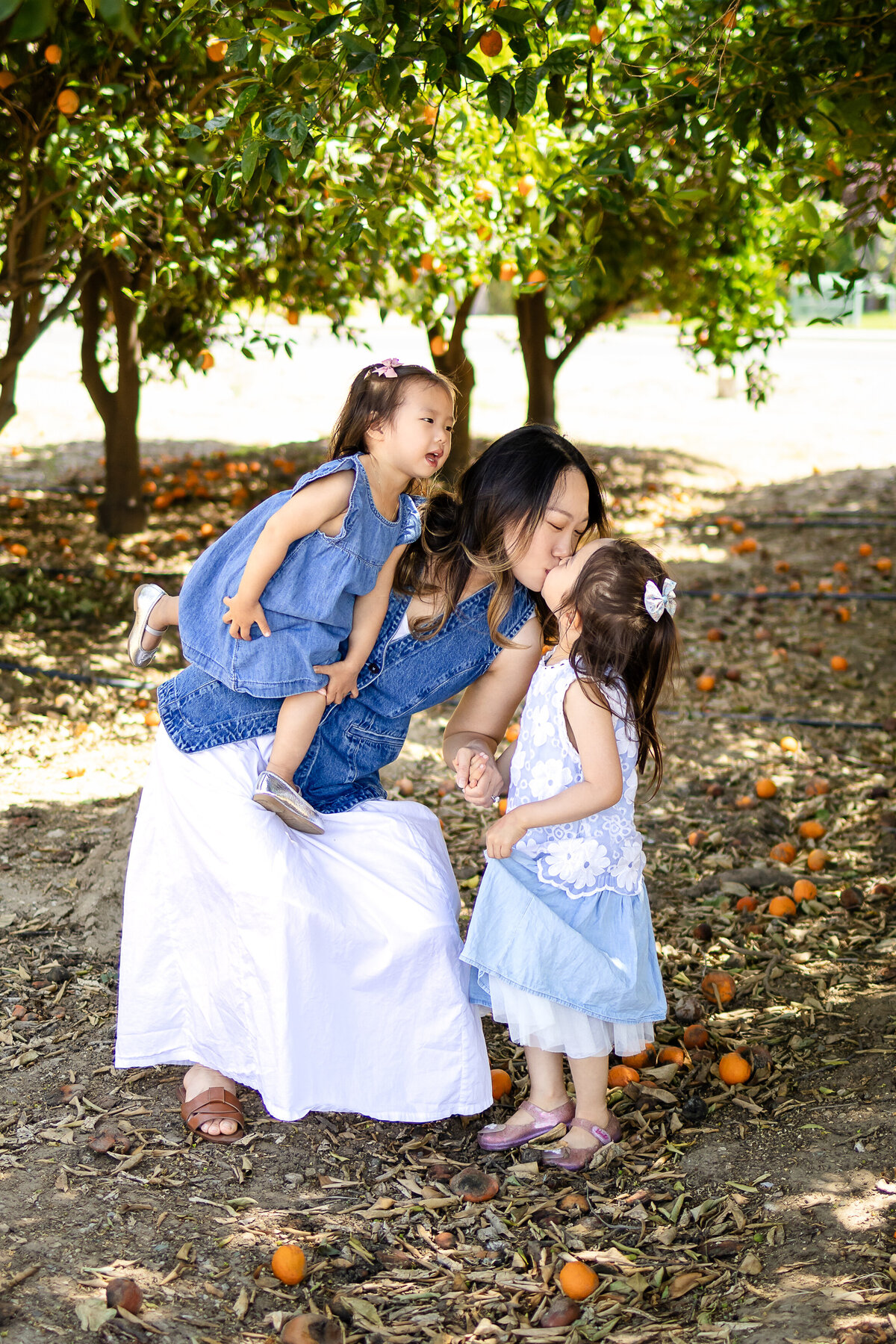 Mom sharing a warm hug with her two daughters children during a playful outdoor session – lifestyle family photography by Ellobelle Photography, San Francisco Peninsula