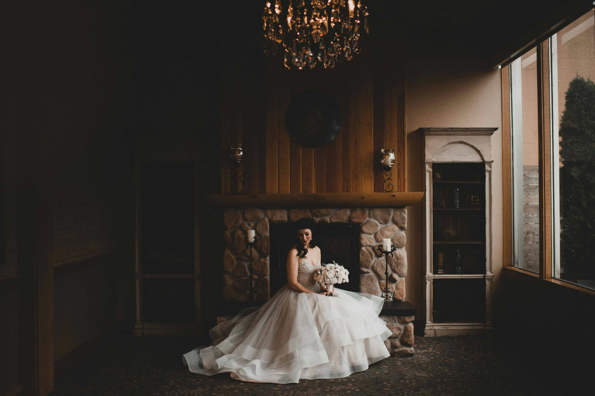 bride in large white dress sitting in front of fireplace at Edgewater Hotel Seattle