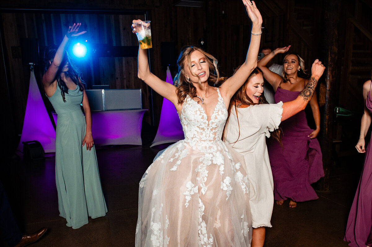 Bride dancing with bridesmaids on the dance floor at The Grove in Murfreesboro, arms up drinking and singing