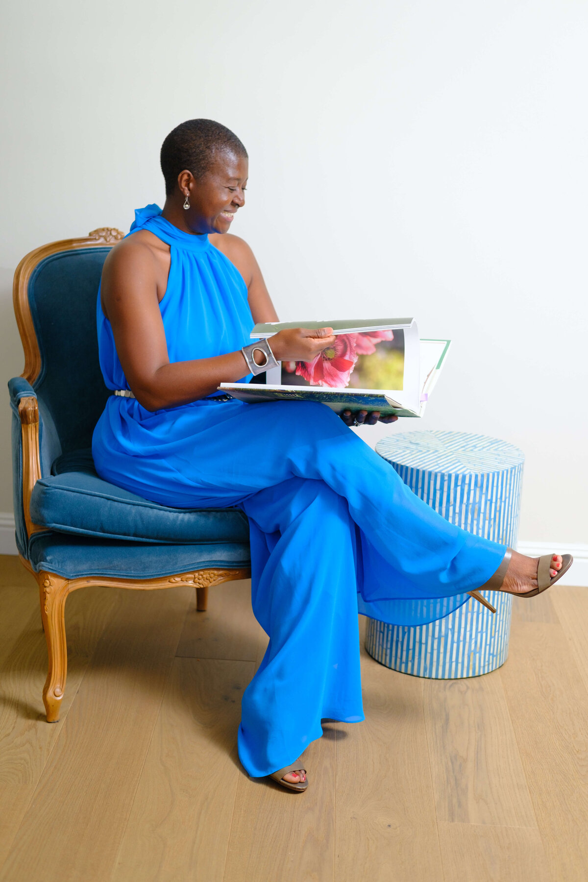 a woman in blue dress sitting in a chair reading a book