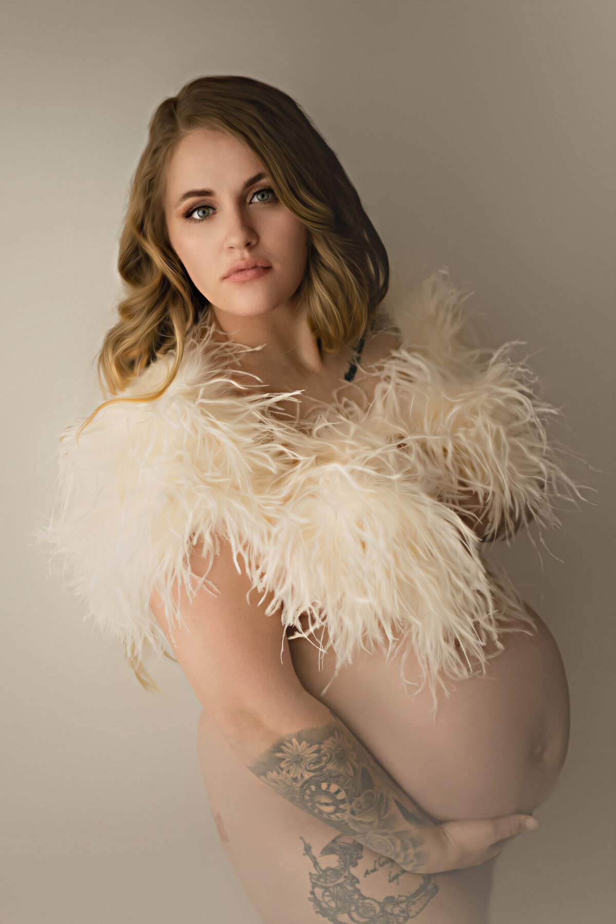 An Iowa maternity photographer image of a pregnant woman standing in a studio covering her top with a white feather boa
