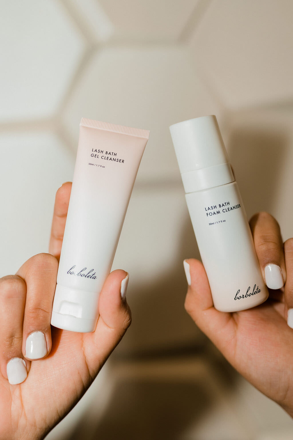 two hands holding two small bottles of skin care products