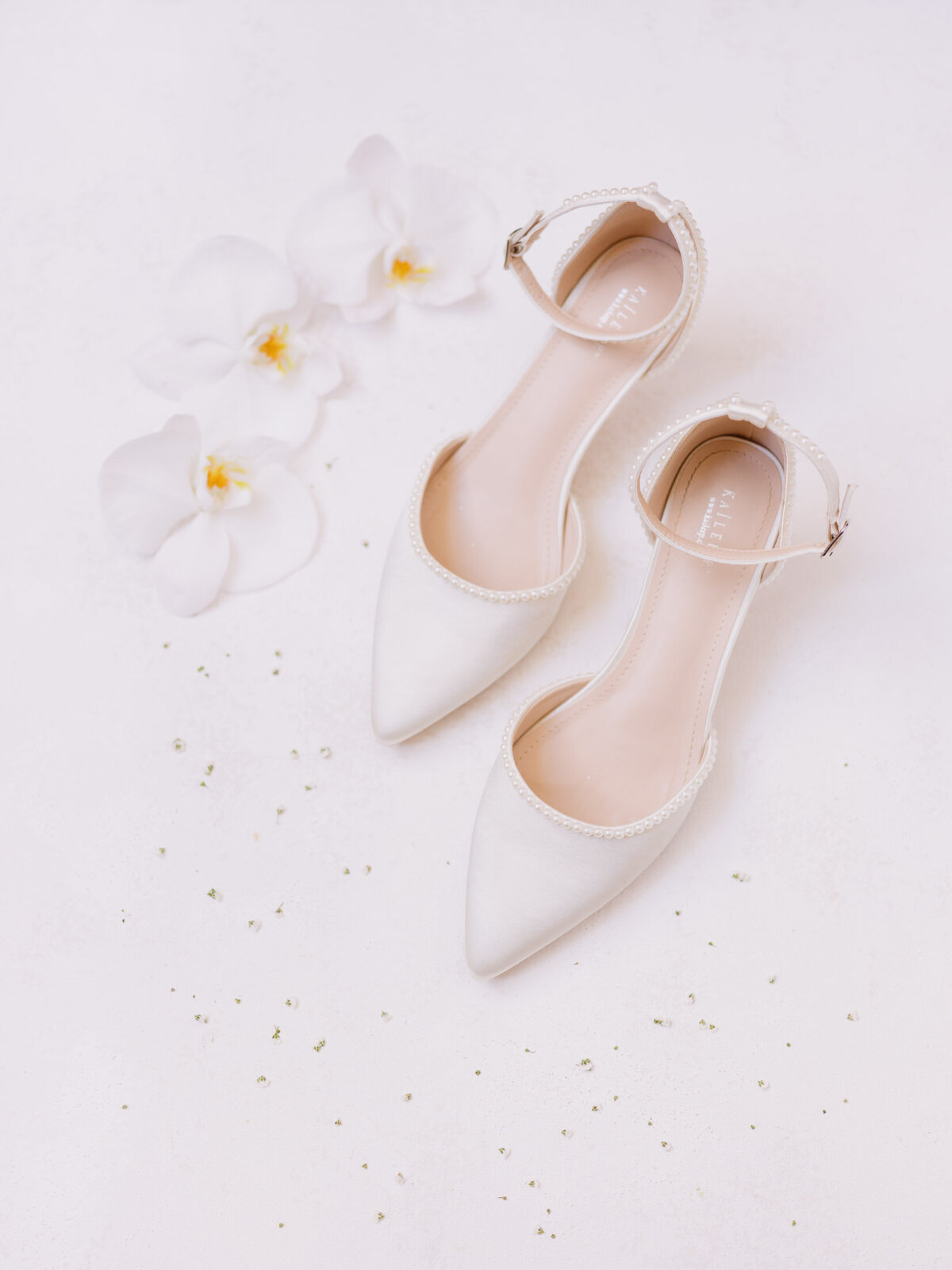 Bridal shoes surrounded by white orchids