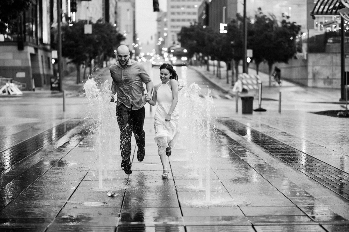 Couple-running-laughing-through-fountain