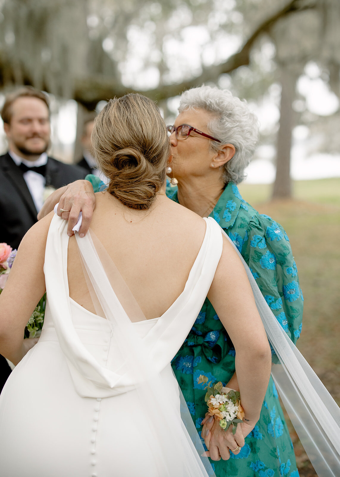 Bride's mother kissing her on the cheek