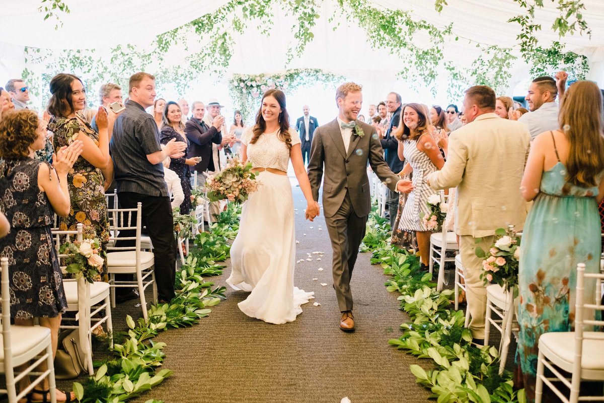This sweet summer wedding ceremony had greens lining the aisle and covering the ceiling of the tent.