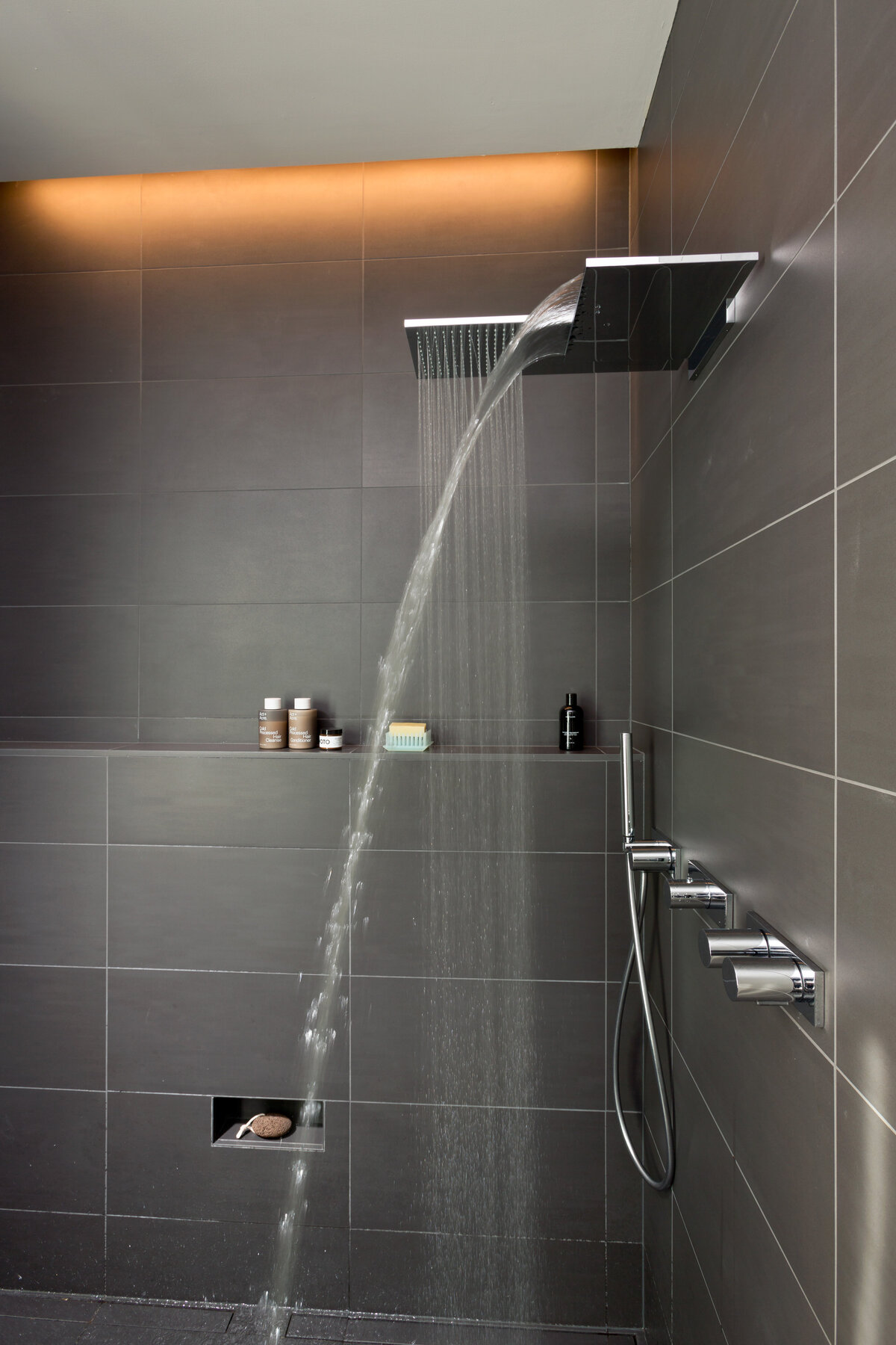 dark grey tiled shower with water running