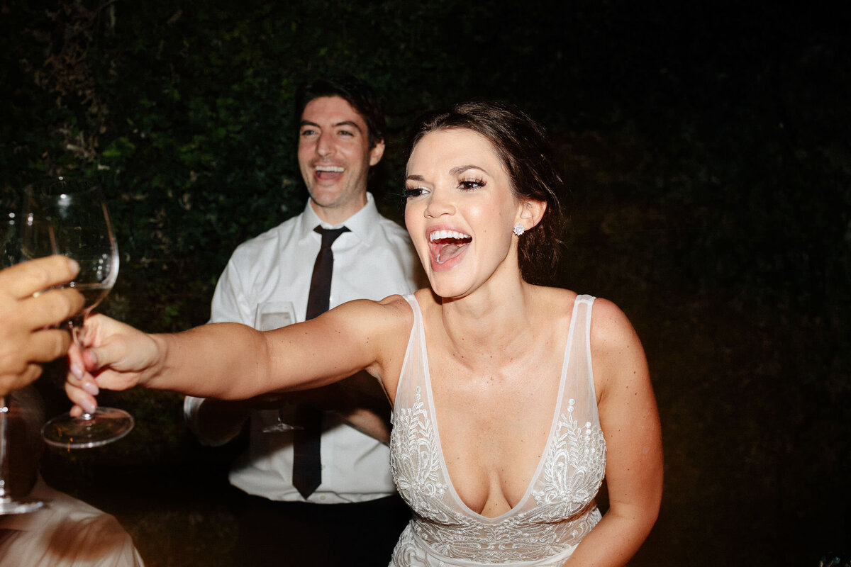 Lake Como Italy wedding reception bride in white lace dress laughing and toasting at night