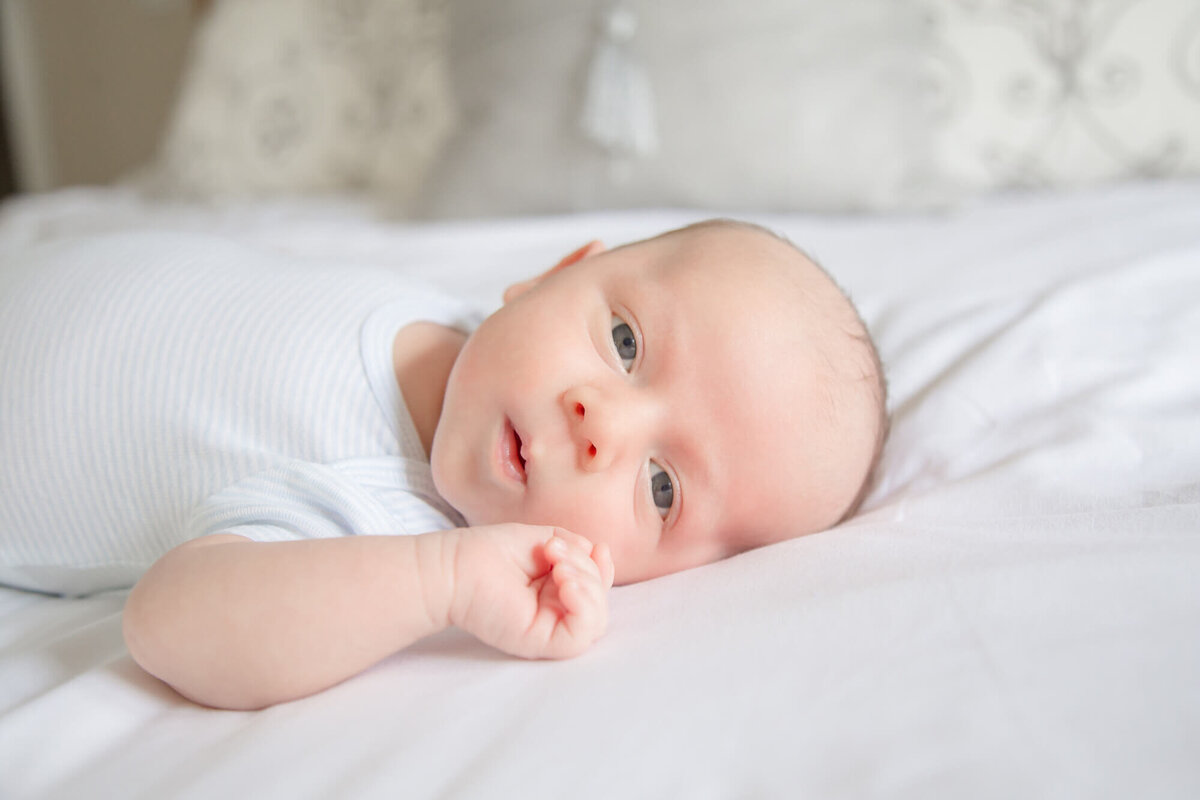 Stunning expression from newborn baby boy  on a white bed