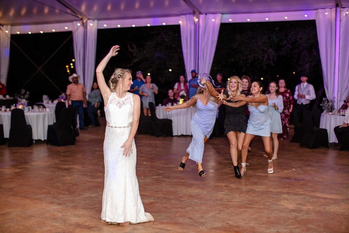 bride tosses bouquet at La Dolce Vita wedding with purple uplighting