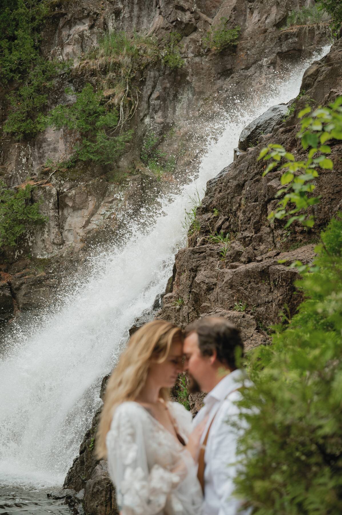 couple kissing front of waterfall