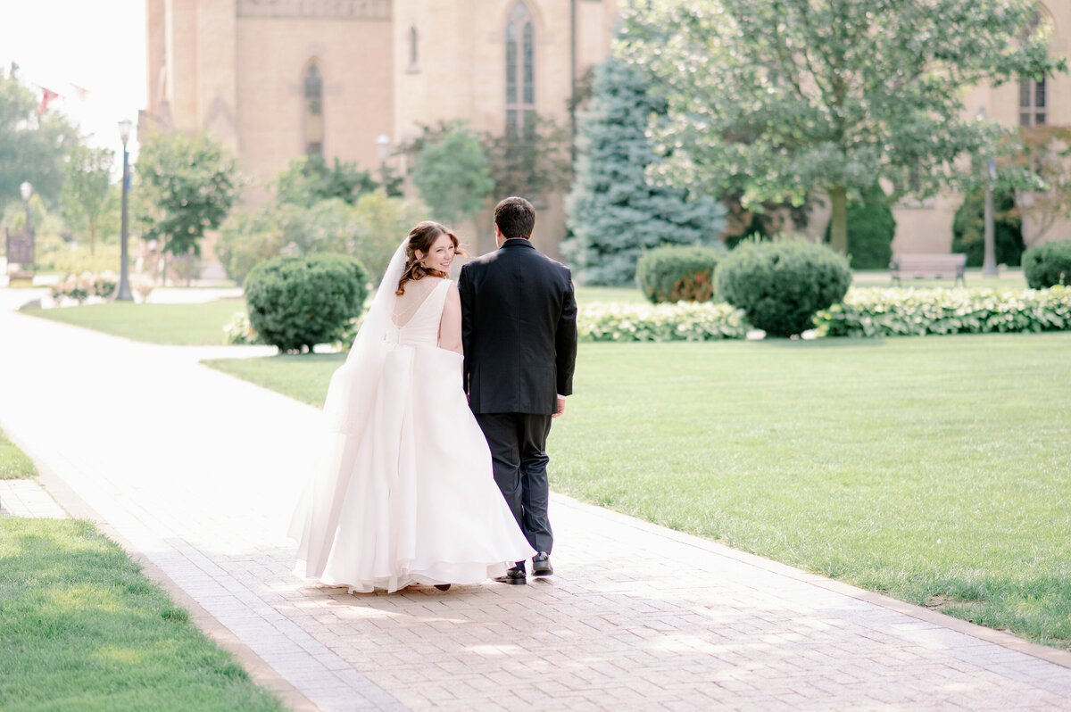 a bride and groom walking on Notre Dame's campus on their wedding day
