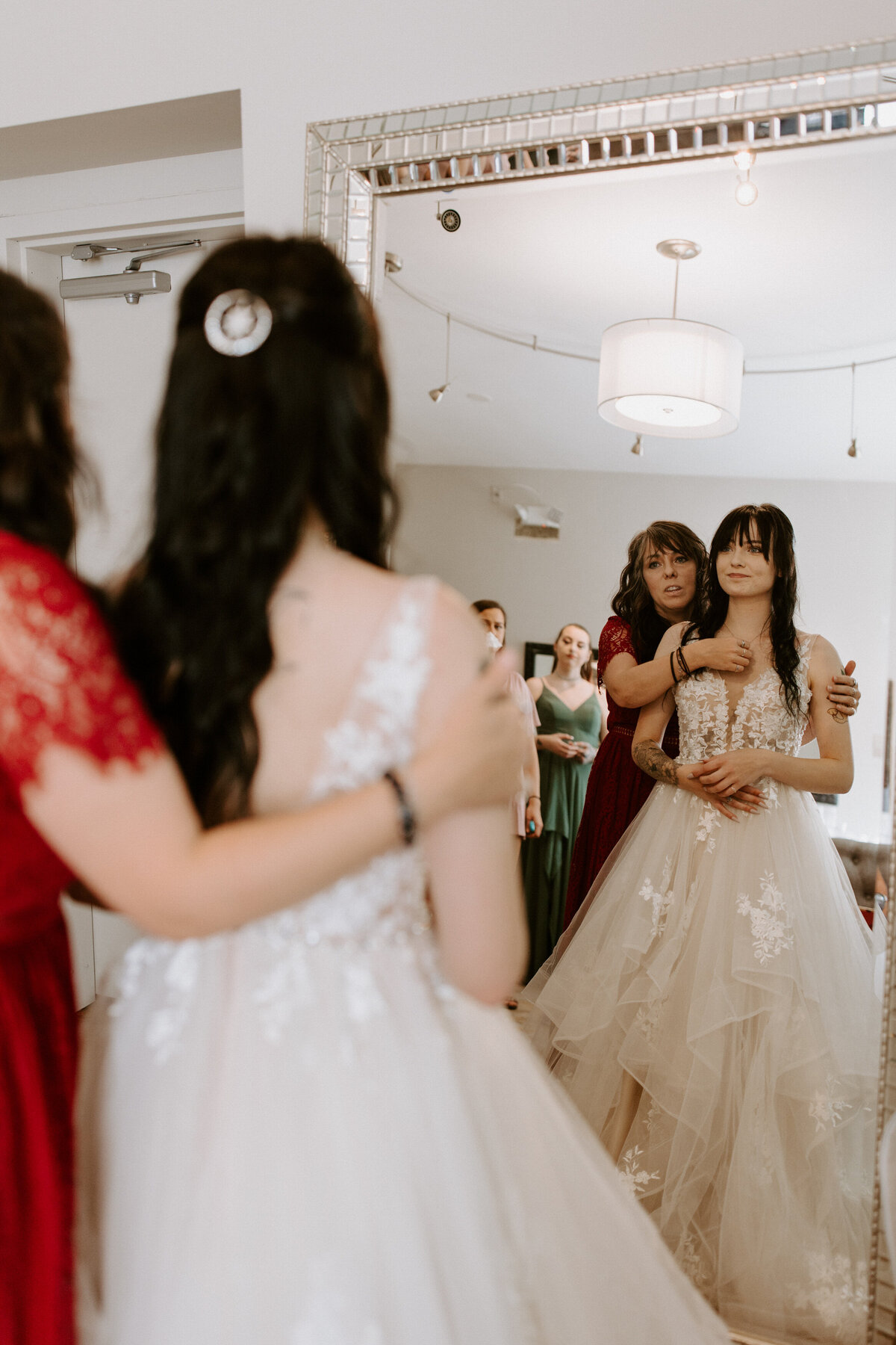 reflection of a person helping a bride adjust her dress