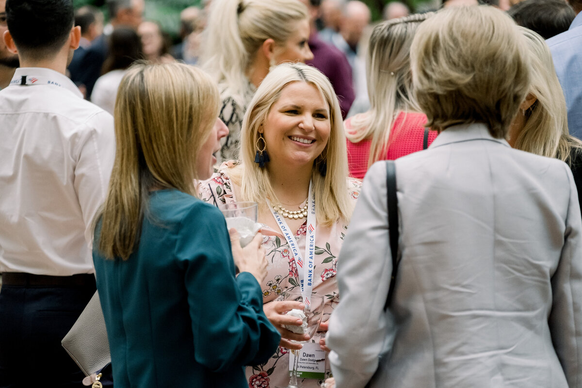A woman smiles while having a conversation with two other women during the conference