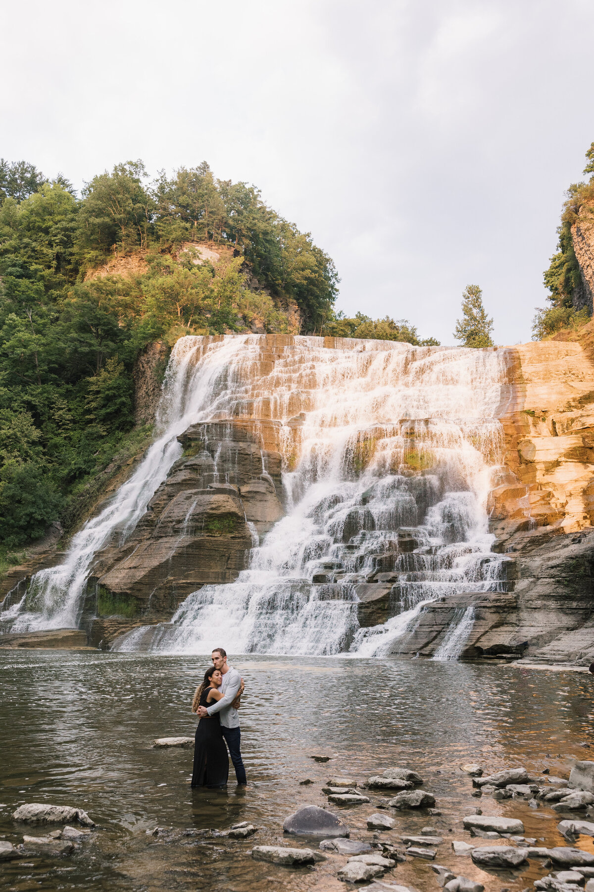 Bride & Groom standing in the waterfall at Ithaca Falls in Ithaca, NY as the sunsets