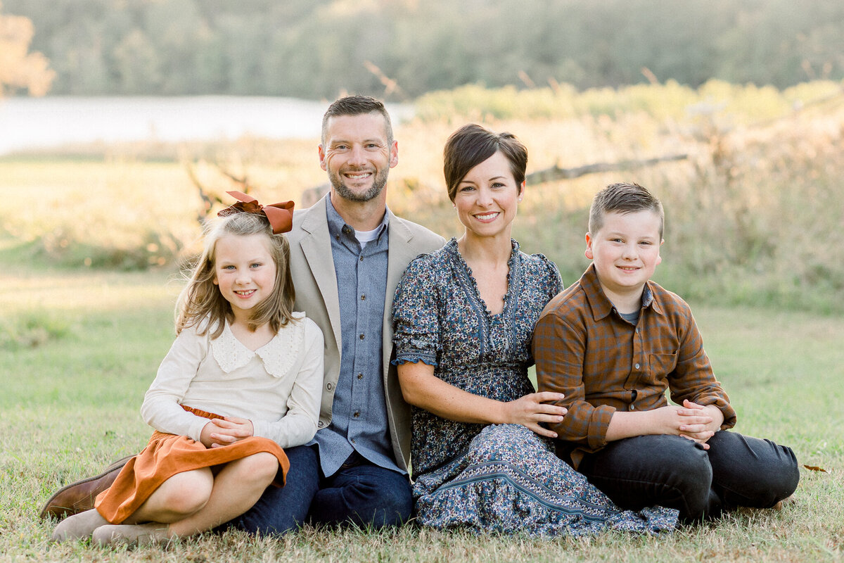 Family of four smiling at each other in front of building. Image captured by Madison, MS Family photographer