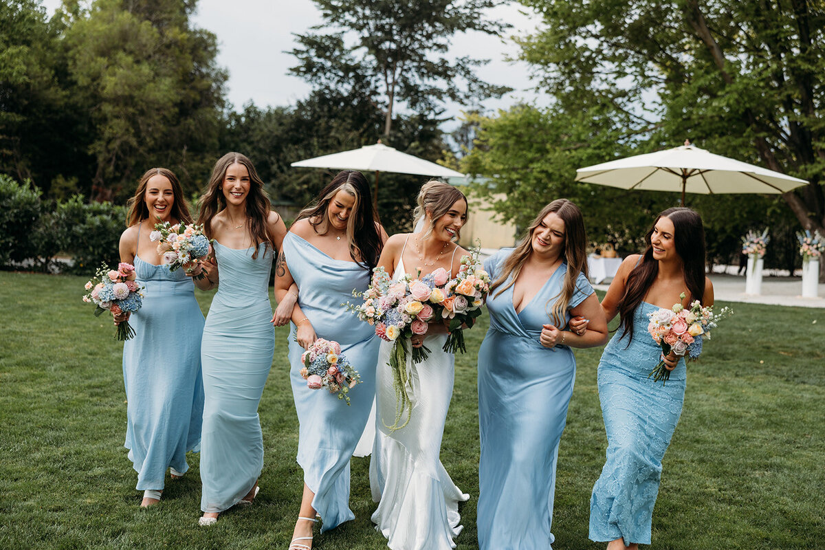 Bride walking arms linked and smiling with her bridesmaids at Poachers Pantry