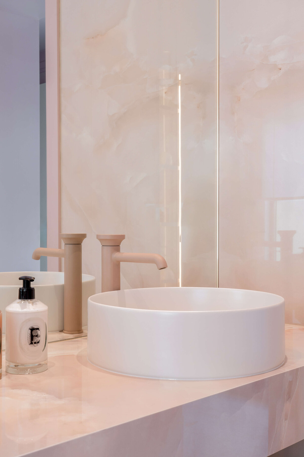 Light pink marble counter with a matte pink faucet and white sink bowl.