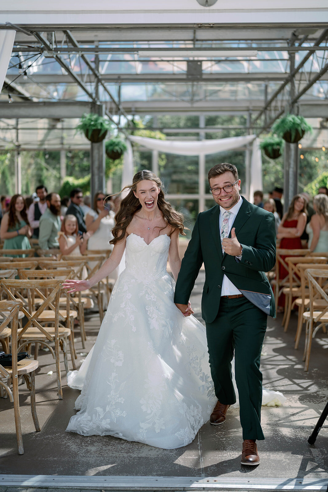 Bride and groom exiting their Ivy House ceremony with big smiles and thumbs up, celebrating their marriage.