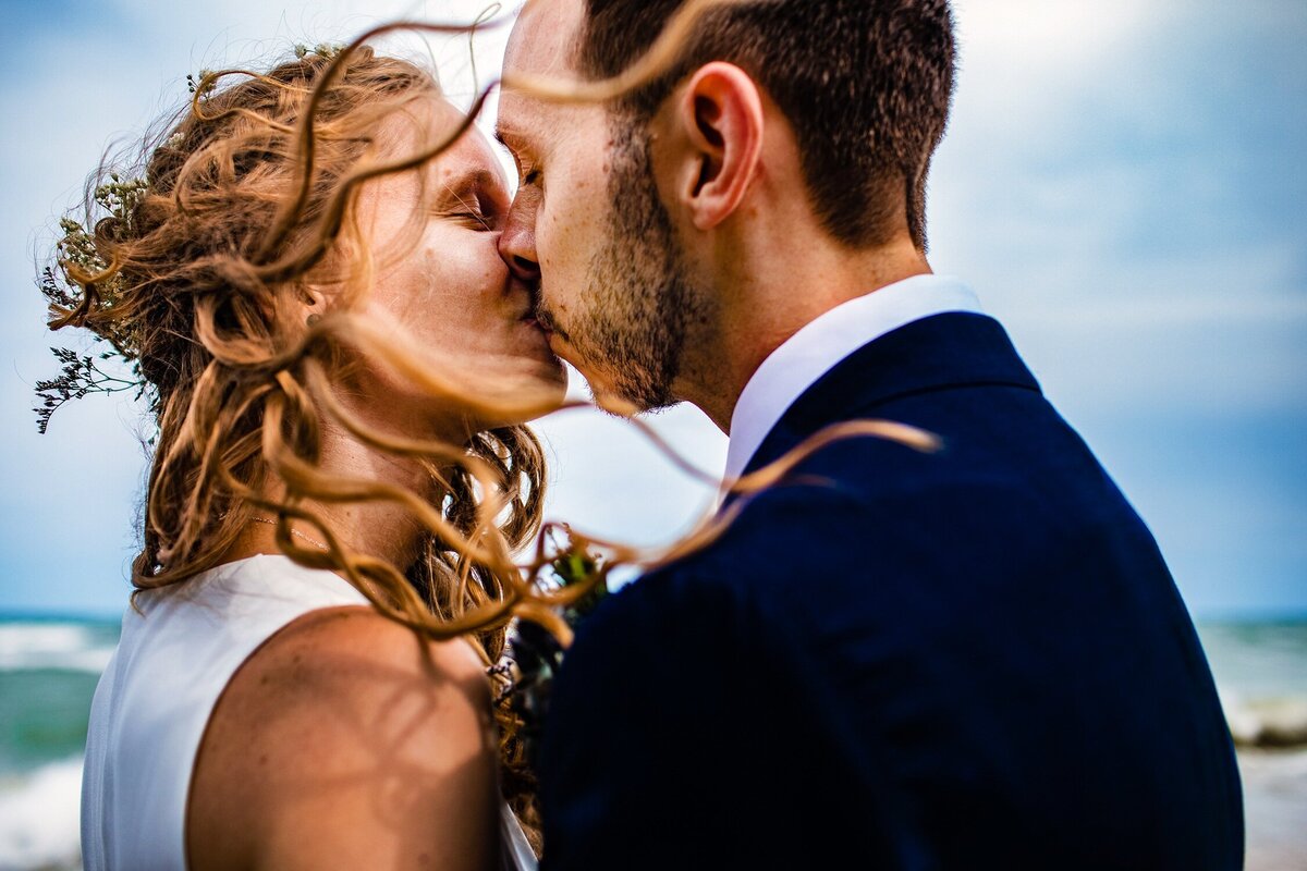 A couple kisses in the wind at an Illinois Beach Resort wedding.
