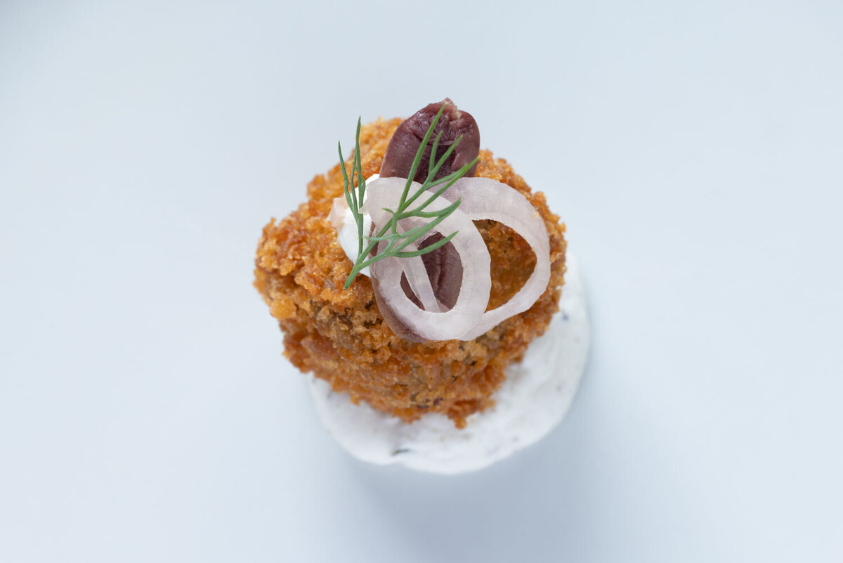 Crispy appetizer topped with onion and herb on white sauce.