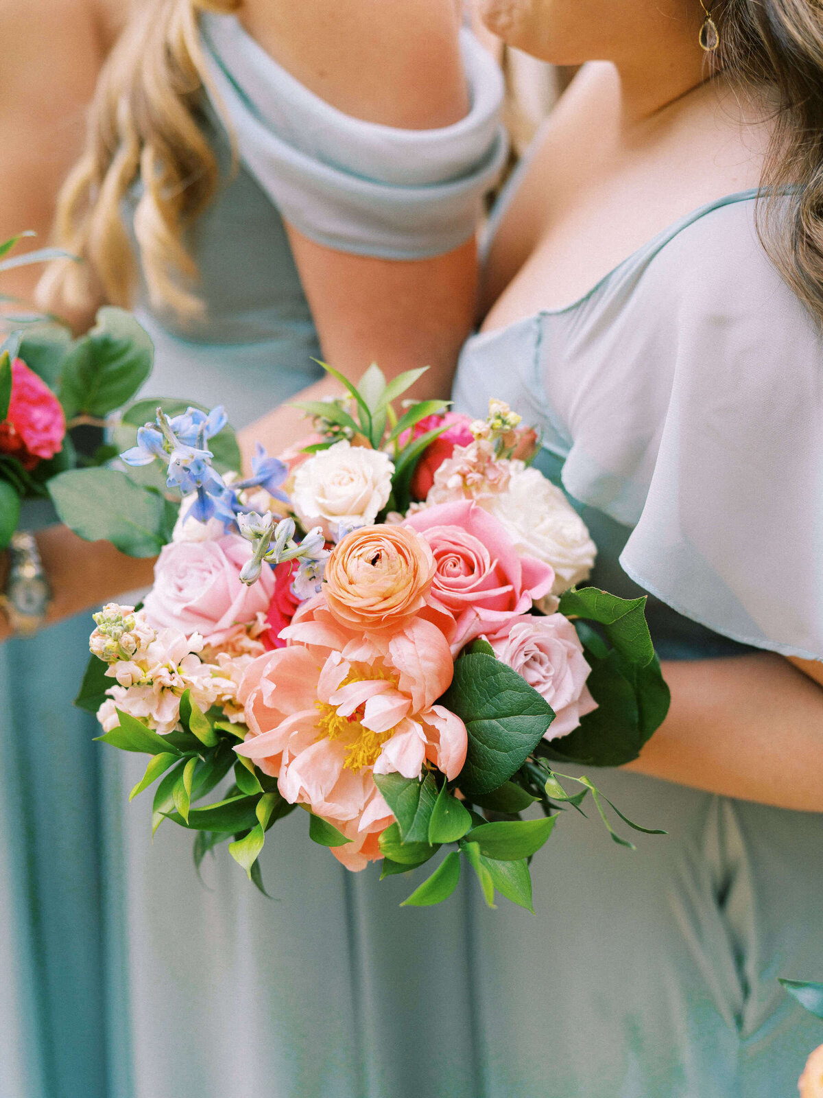 Bridesmaids wearing aqua dresses holding colorful spring wedding bouquets