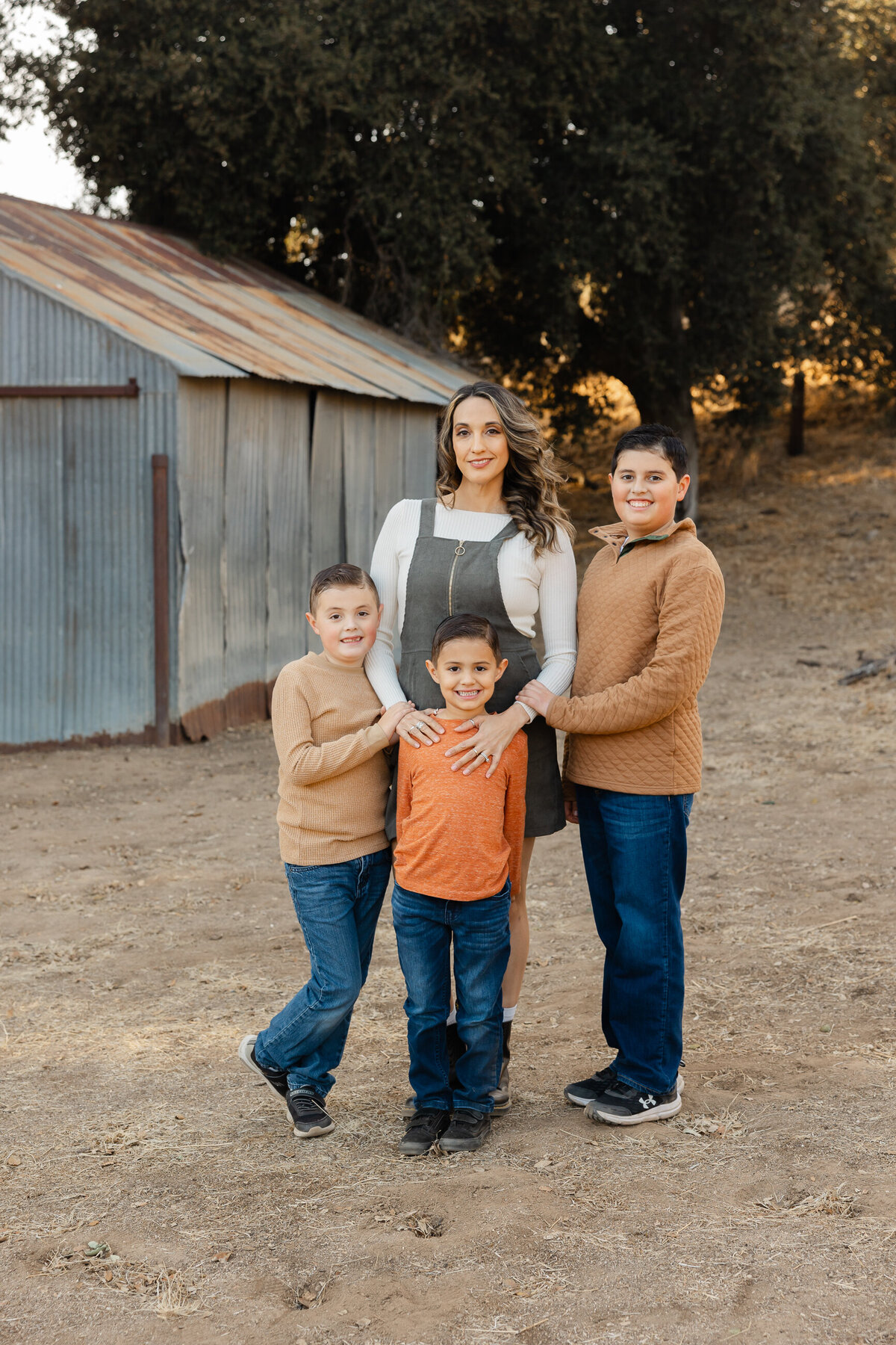 Parents standing with their son in front of rustic barn backdrop during fall session. Photographed by Yucaipa family photographer Kaitlyn Dawn Photography.