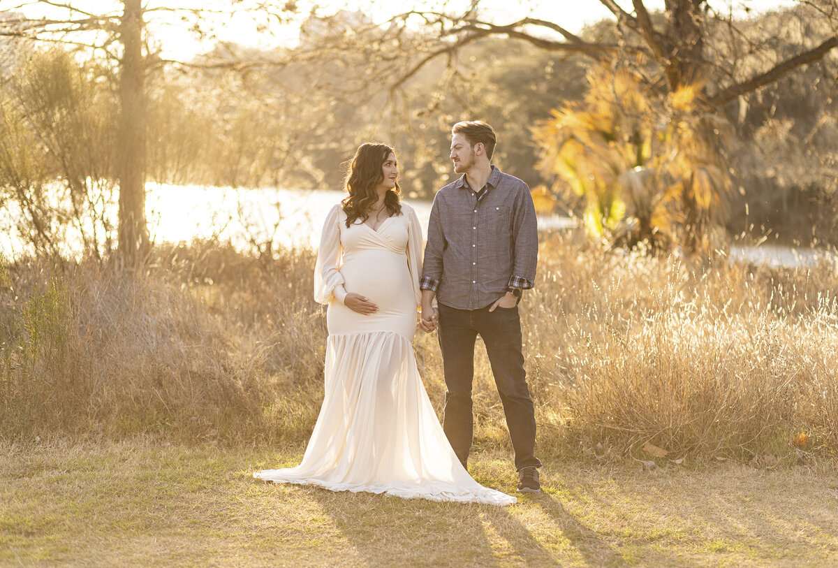 mom and dad looking at each other outside with golden sun flare