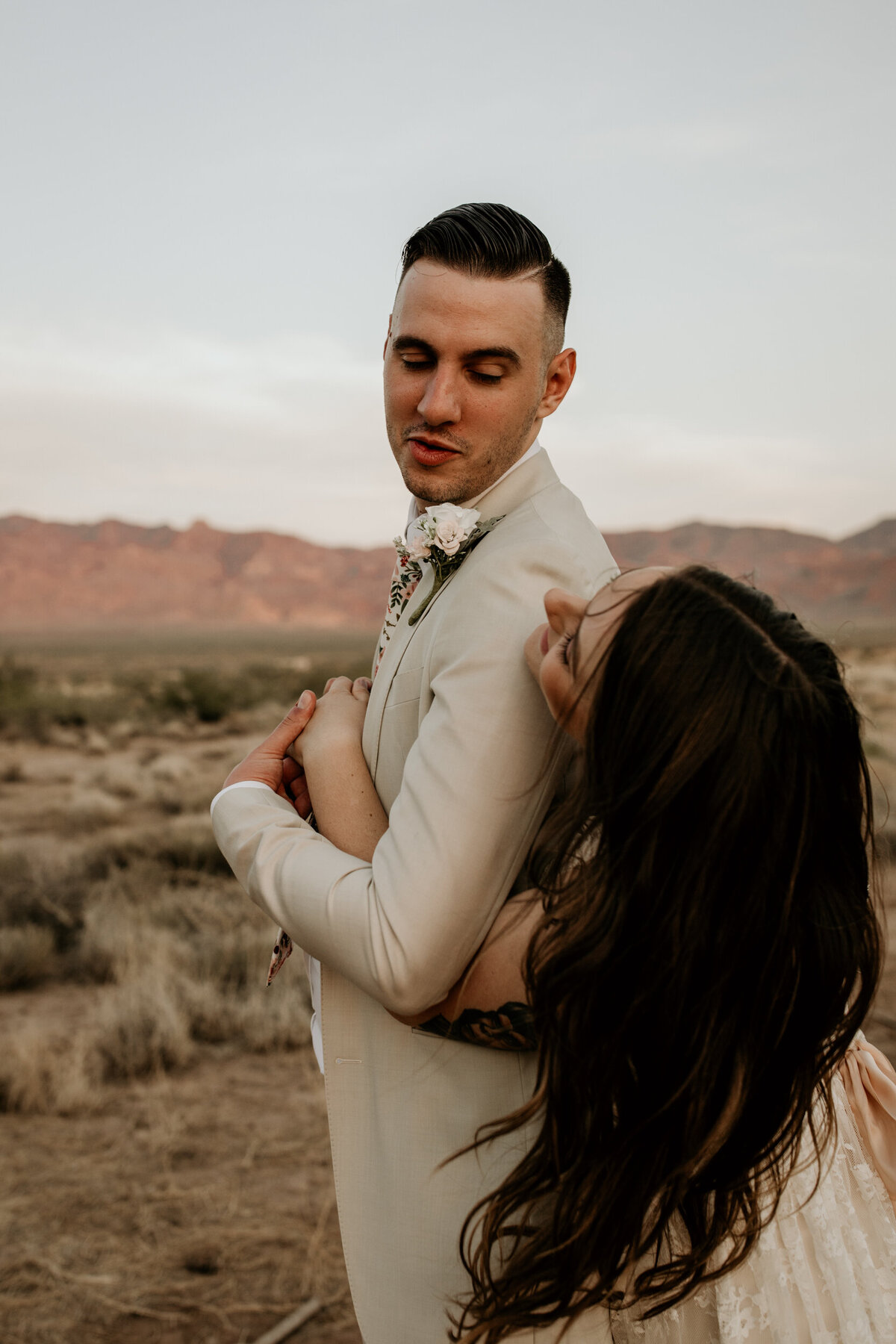 bride hugging groom from behind in the desert