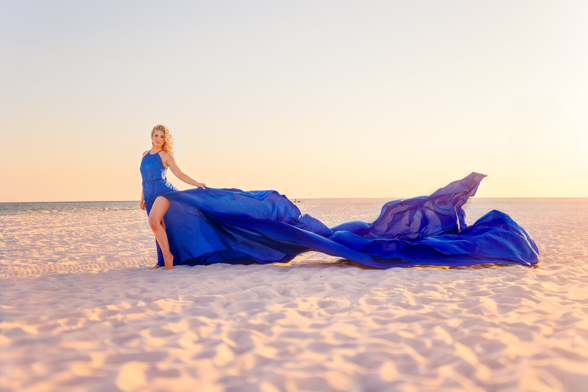 Flying dress pulls to the side of a girl as she poses along the beaches of Orange Beach, Alabama.