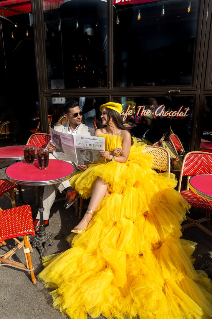 Paris cafe couple photoshoot, yellow dress with matching beret, Save the Date newspaper prop, authentic Parisian moment