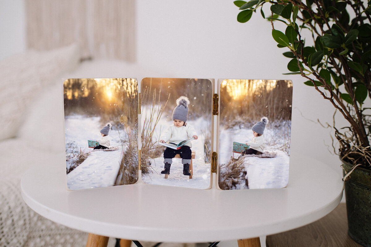 exempelbild på en handgjord träprodukt bestående av tre trätavlor som sitter ihop med foton på en flicka som sitter och tittar i en bok på vintern i motljus