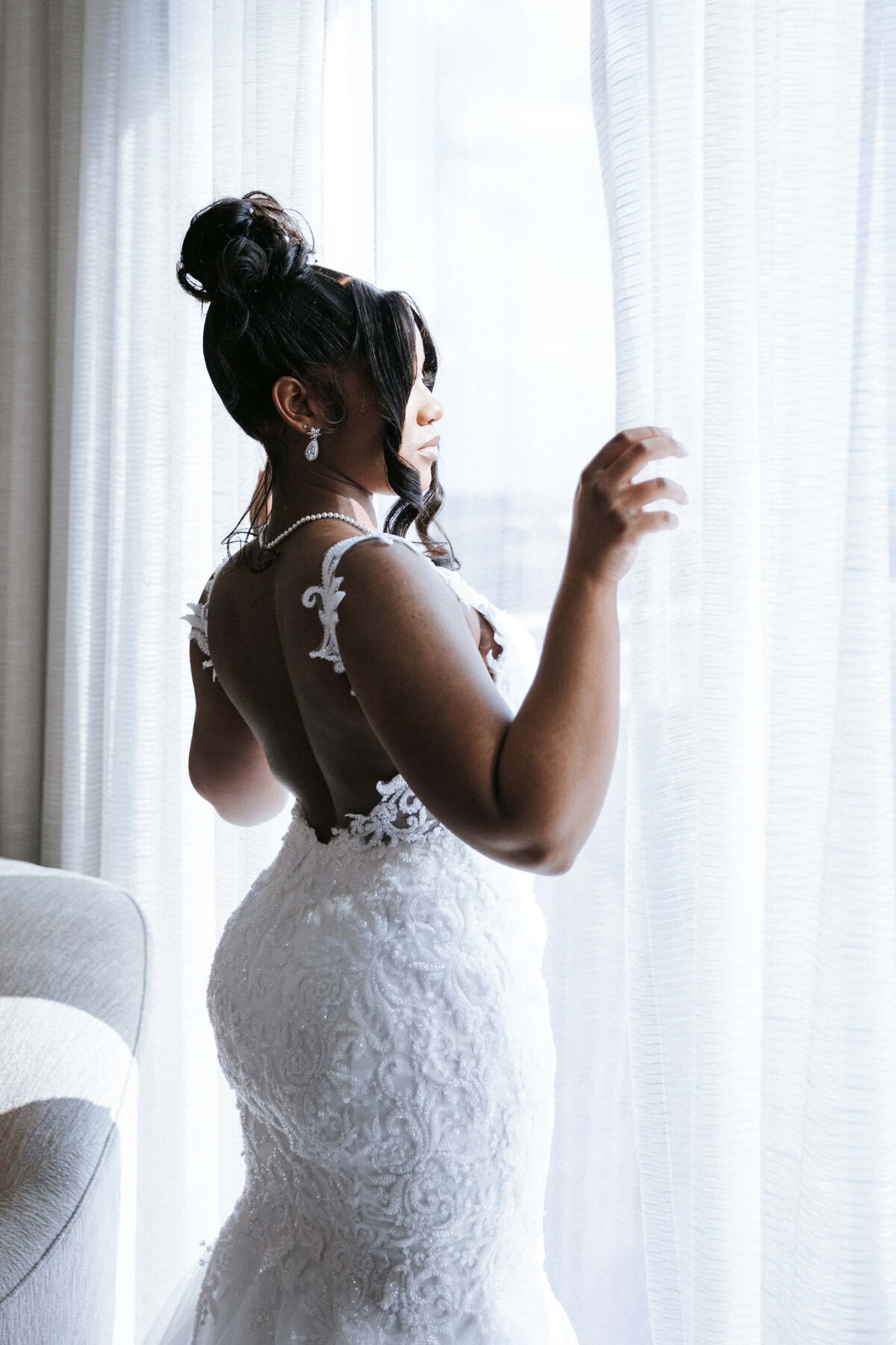This elegant bridal portrait of a Black bride was captured by Phavy Photography, a Jacksonville wedding photographer. Posed beside soft sheer curtains, the natural light highlights the details of her lace gown and graceful presence. With a blend of editorial beauty and documentary storytelling, Phavy Photography captures timeless, personal moments for modern weddings in Downtown Jacksonville.