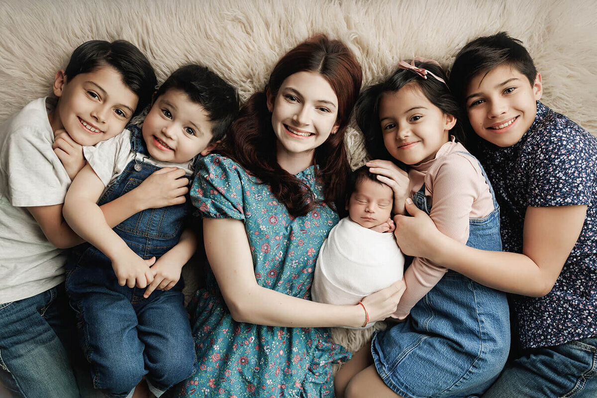 Large Colorado family siblings holding their newborn baby brother and smiling