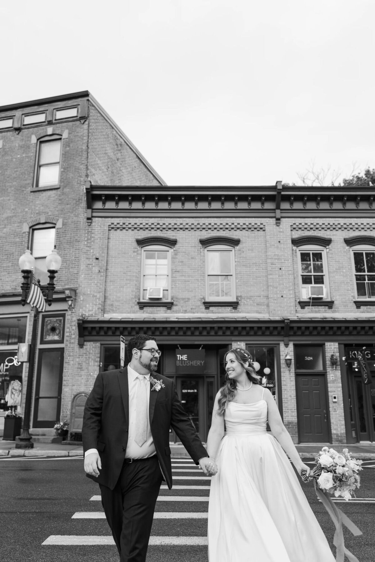 Bride and groom cross the street in front of the Blushery on Beacon's Main Street outside the Roundhouse Hotel