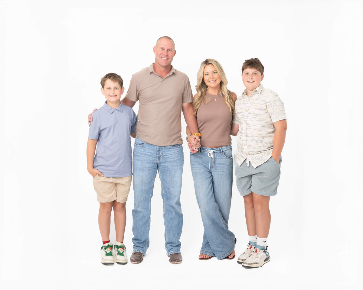 Beautiful family in denim and neutrals with elementary aged boys in a full body white-studio portrait, captured by Allison Amores Photography 