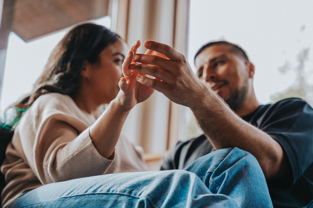 The couple snuggles up on a sofa and holds hands 