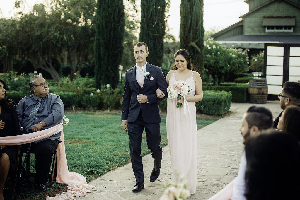 Wedding Photograph Of Groomsman And Bridesmaid Holding a Bouquet While Walking Los Angeles