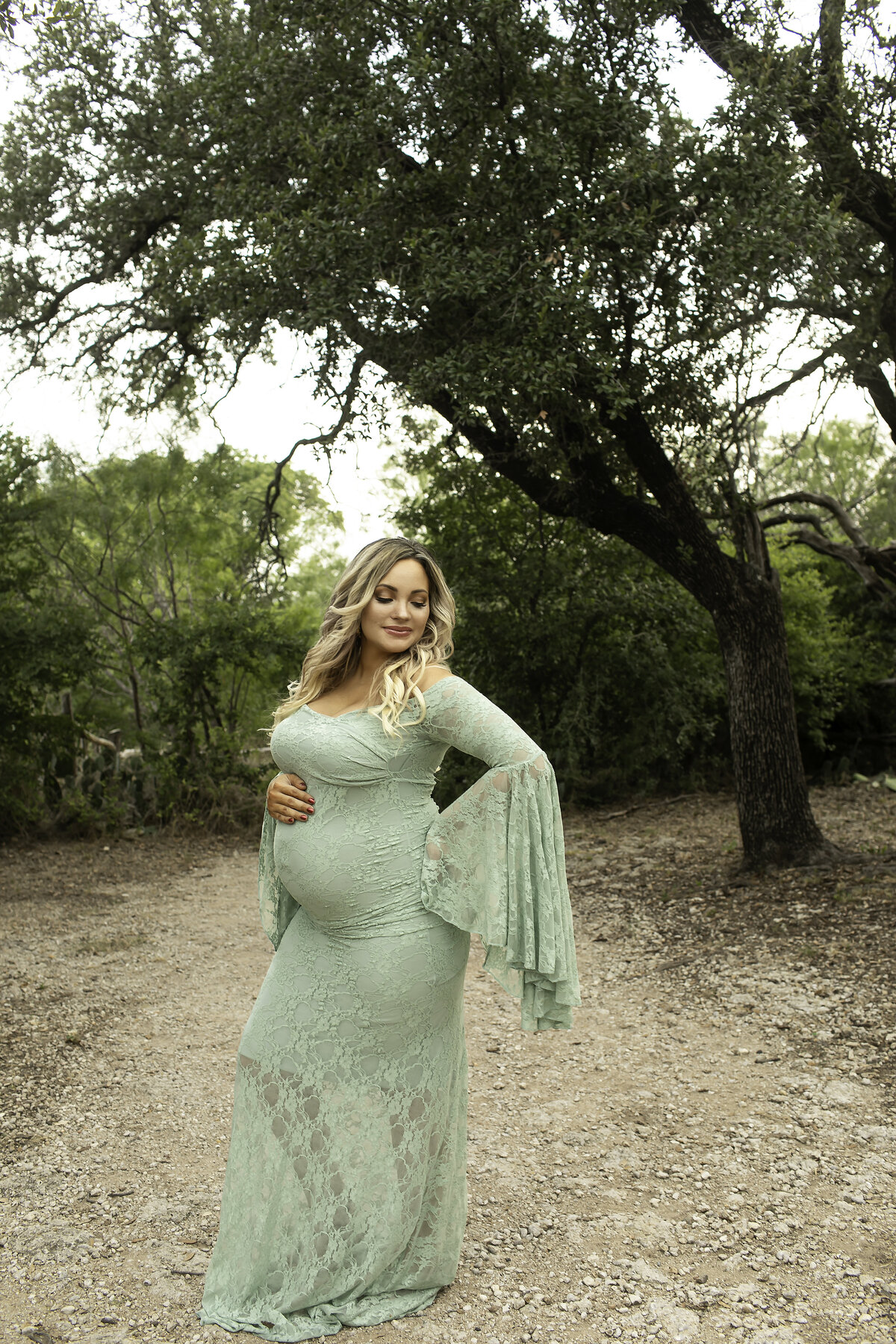 A joyful maternity photo of the expectant mom standing in the park, proudly showing off her sweet belly while smiling and enjoying the moment, beautifully captured by Chunky Monkey Photography.
