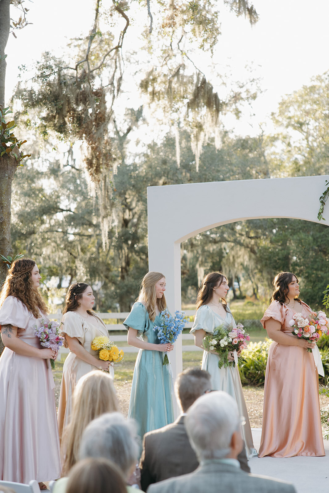 Bridesmaids walking toward the ceremony arch at Uliana Estate, a dreamy Lakeland wedding venue.


