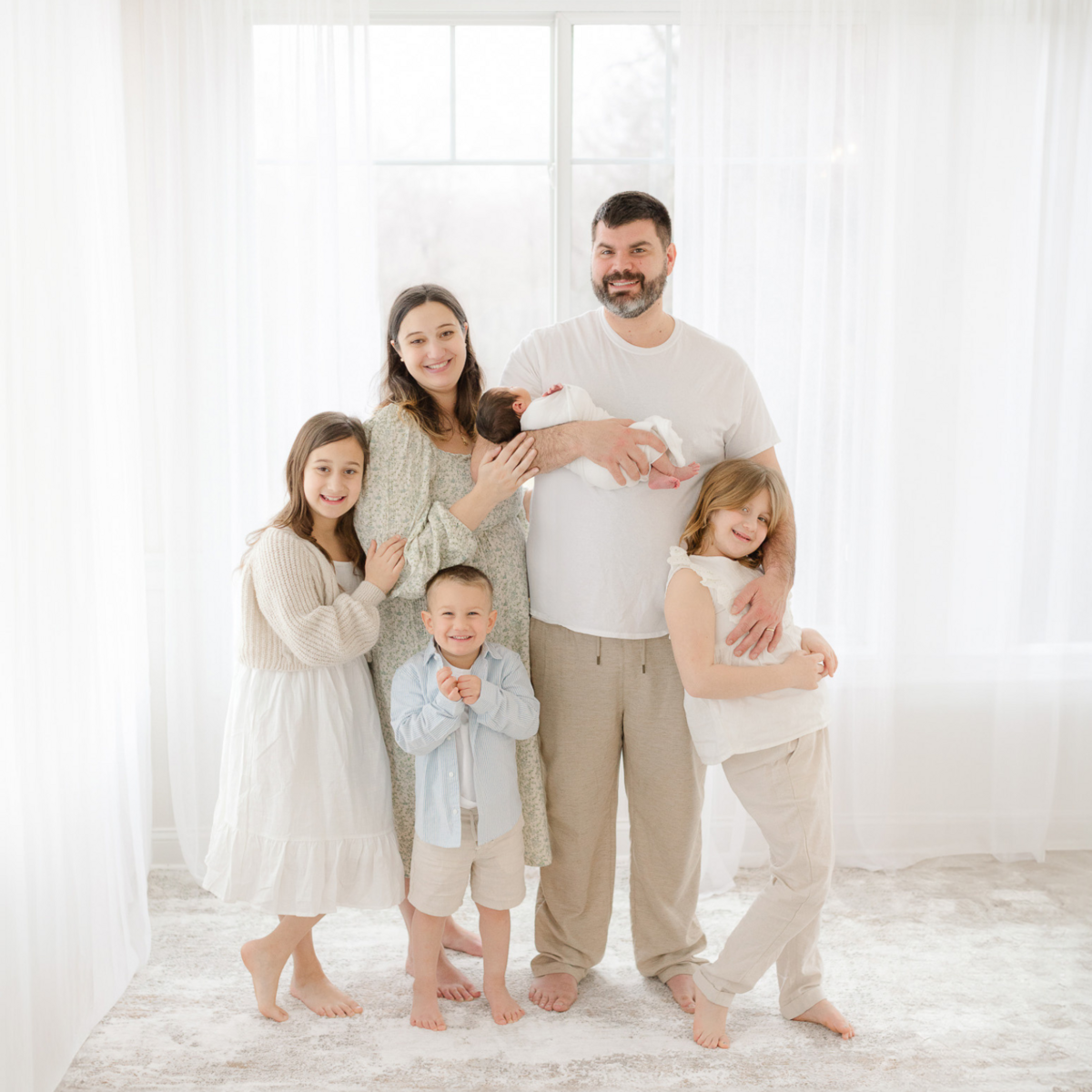 family of 6 smiles at the camera during newborn photoshoot