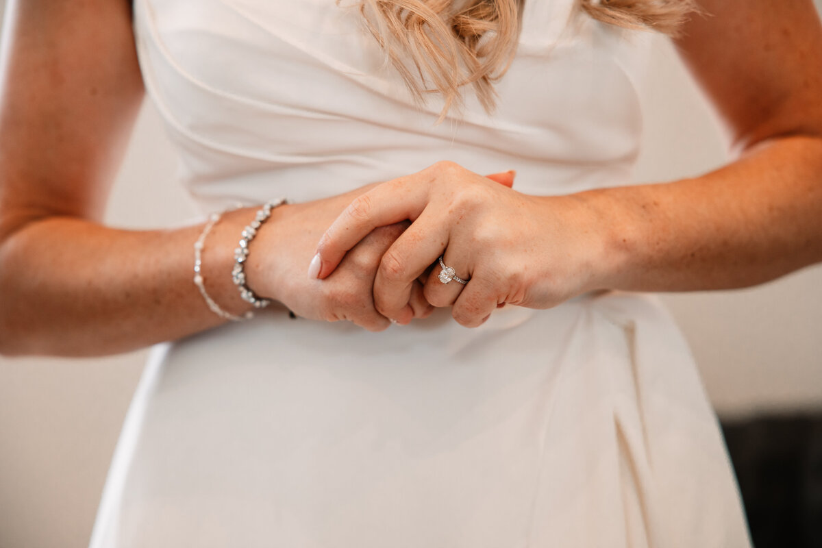 Details of a bride holding her hands in front of her in her dress