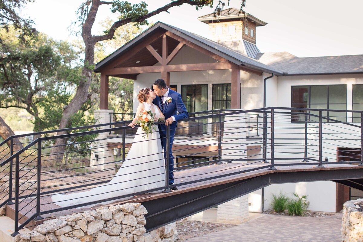 bride and groom kiss on bridge at Hayes hollow at Hidden Falls in texas hill country