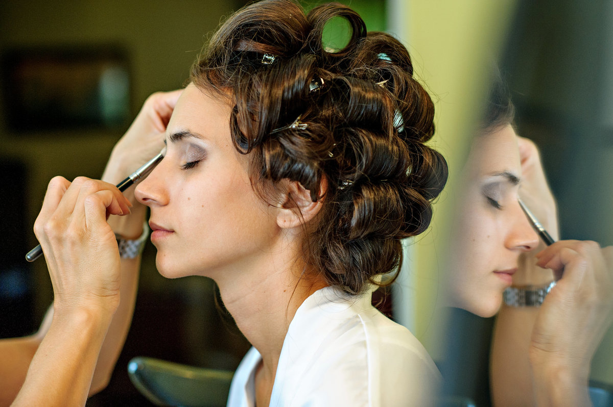 A bride getting her hair and makeup done before her wedding at her parent's house.