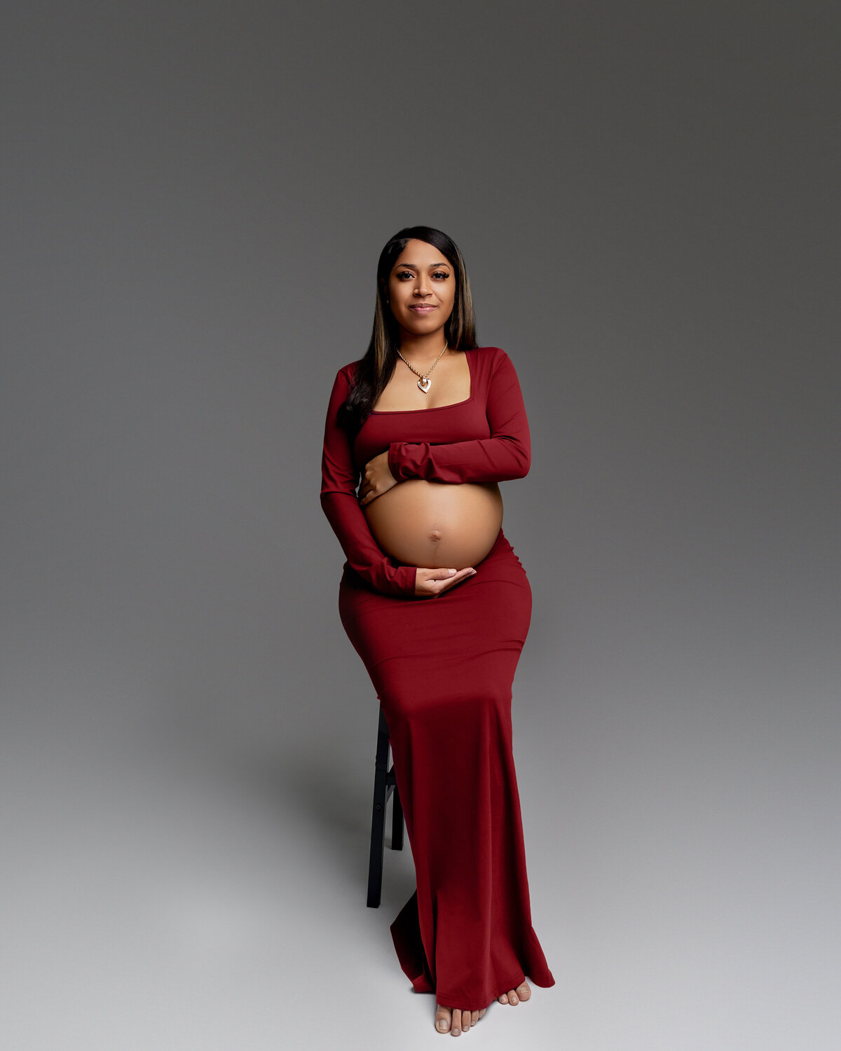 The expecting mother stands gracefully, cradling her belly with a serene expression, capturing the beauty and excitement of her pregnancy. Captured by Inland Empire maternity photographer Kaitlyn Dawn Photography.