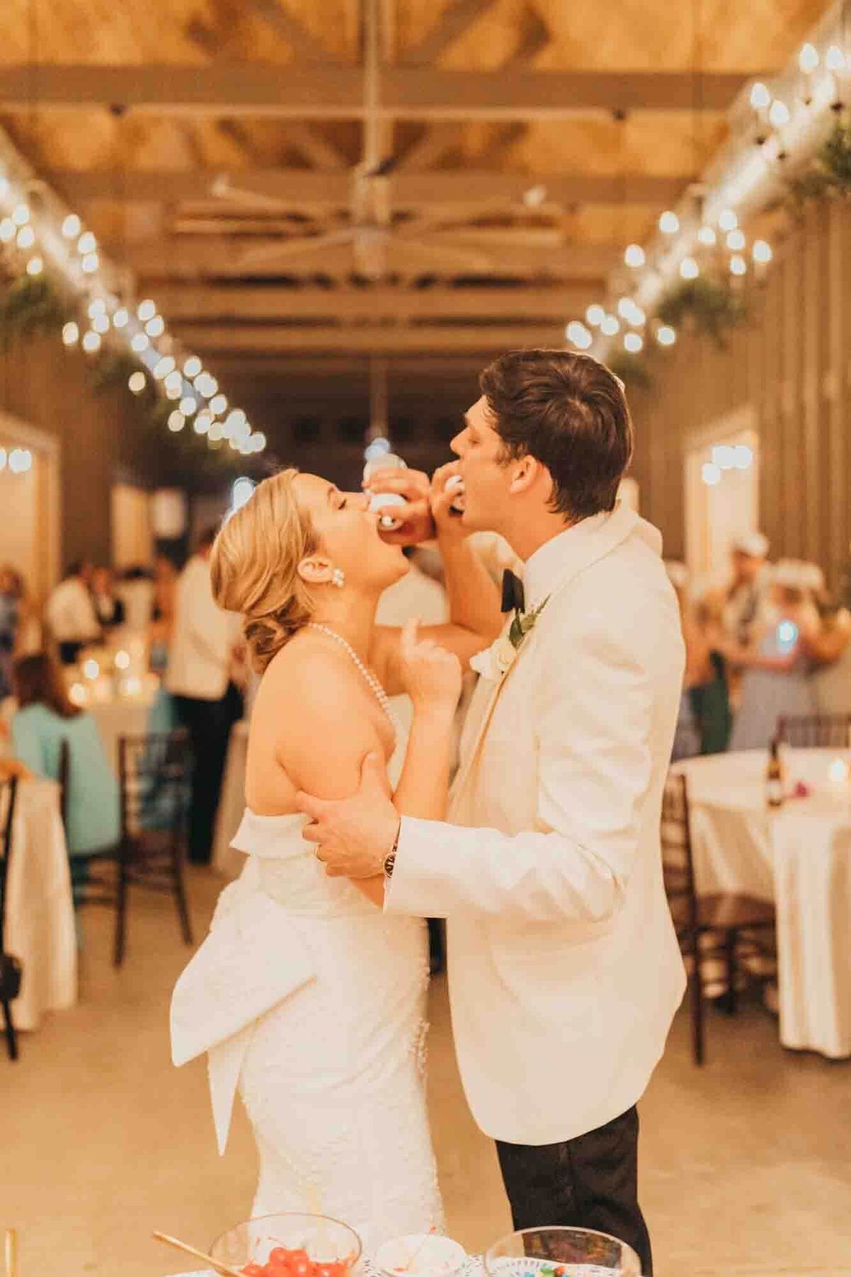 bride and groom feed each other whipped cream from their ice cream bar at their reception.