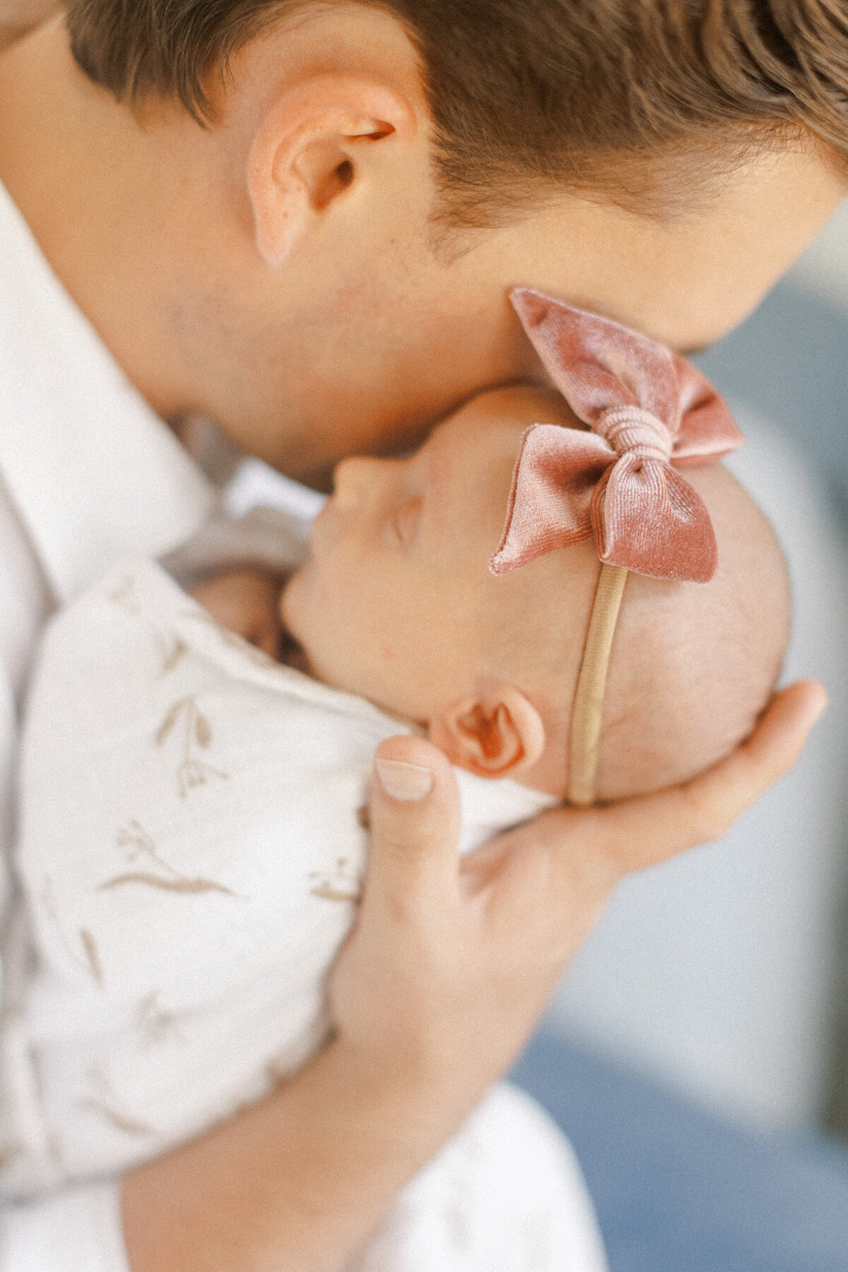 dad holds newborn baby daughter close to face