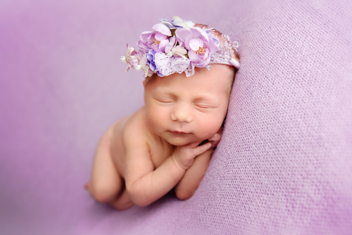 st-louis-newborn-photographer-baby-curled-up-sleeping-on-purple-plush-with-flower-crown-on